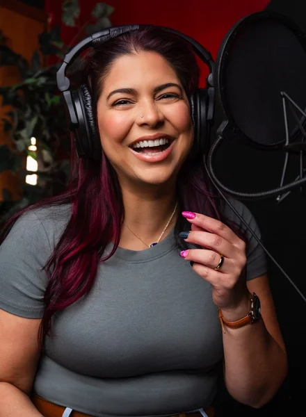Victoria Rojas laughing at the microphone in her recording booth