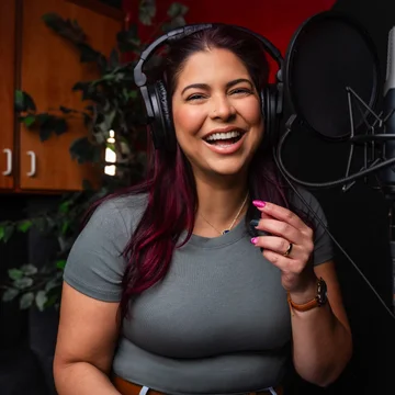 Victoria Rojas laughing at the microphone in her recording booth