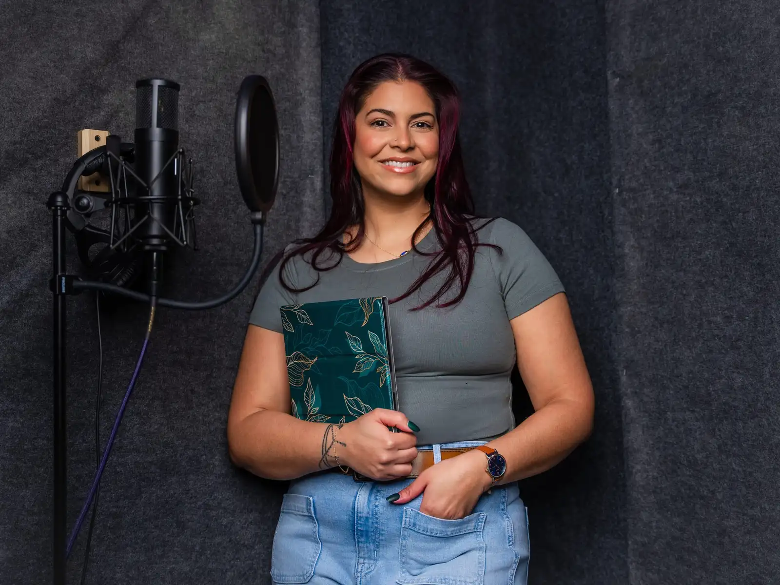Victoria Rojas standing in her recording booth beside a microphone and pop filter