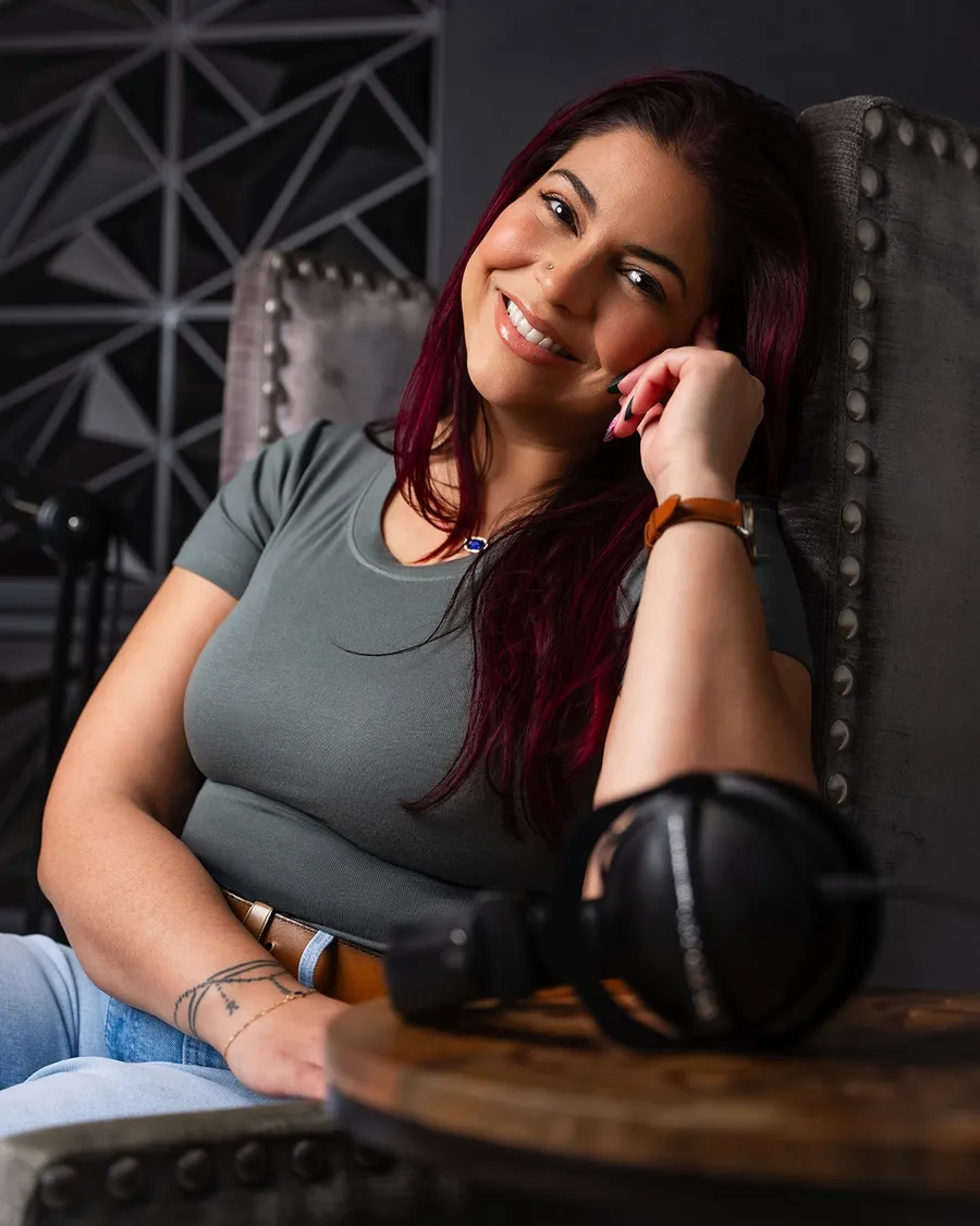 Victoria Rojas seated in her studio beside a pair of over-ear headphones, acoustic panelling behind her